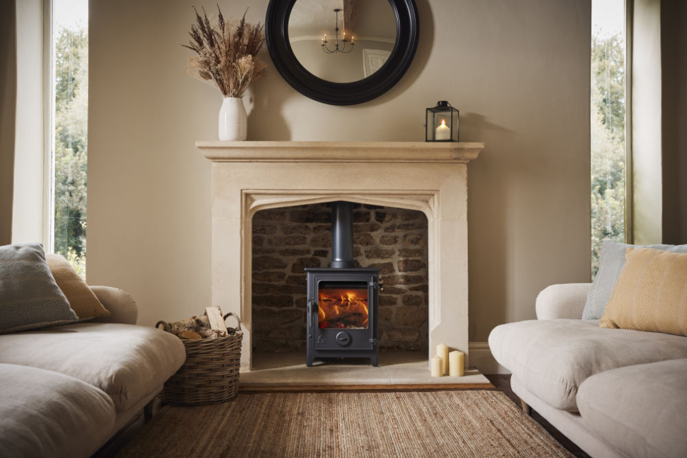 Black wood burning stove in a cream stone fireplace between two sofas